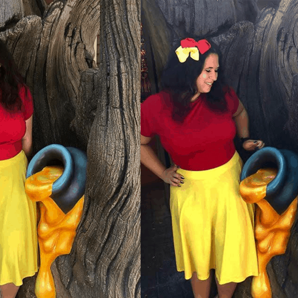 Girl in red shirt and yellow skirt posing next to tree with honey pot