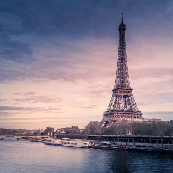 Eiffel Tower (a large metal tower) on the bank of a river at sunset