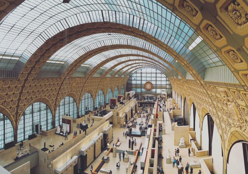 Museum gallery with vaulted ceiling and curved roof. There are windows and gold ornate art-deco tiles decorate the walls