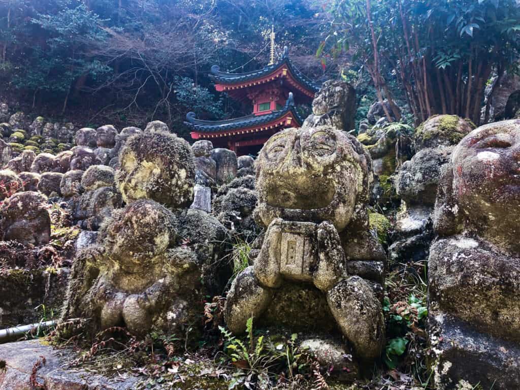 Lines of many small Buddhist statues in front of a Japanese temple