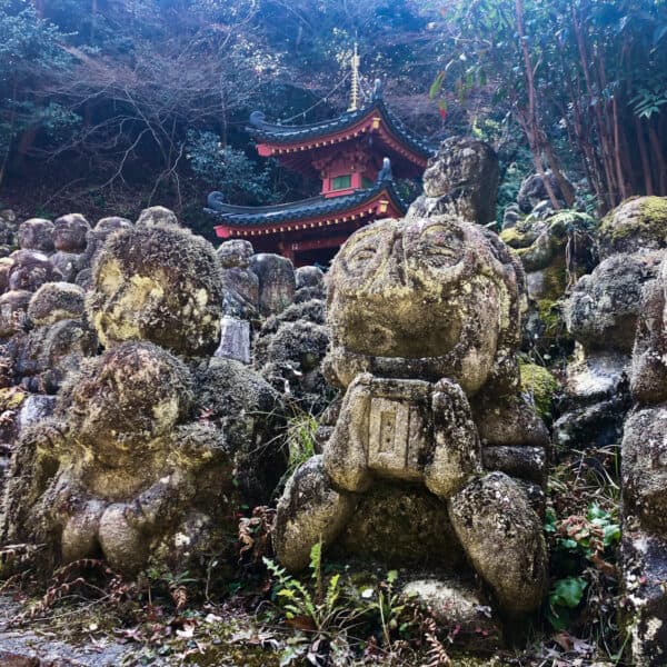 Lines of many small Buddhist statues in front of a Japanese temple
