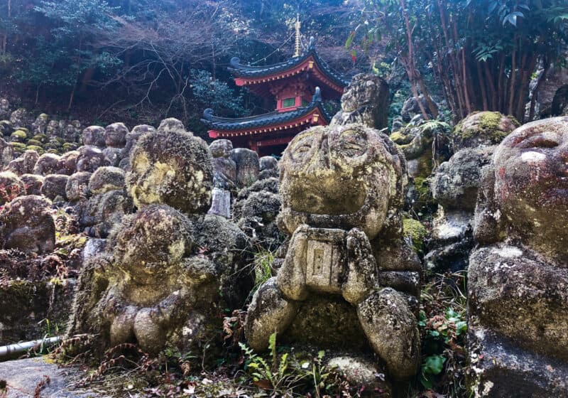 Lines of many small Buddhist statues in front of a Japanese temple