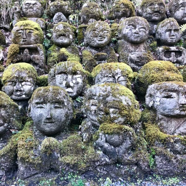 Many stone statues stacked next to each other covered in moss