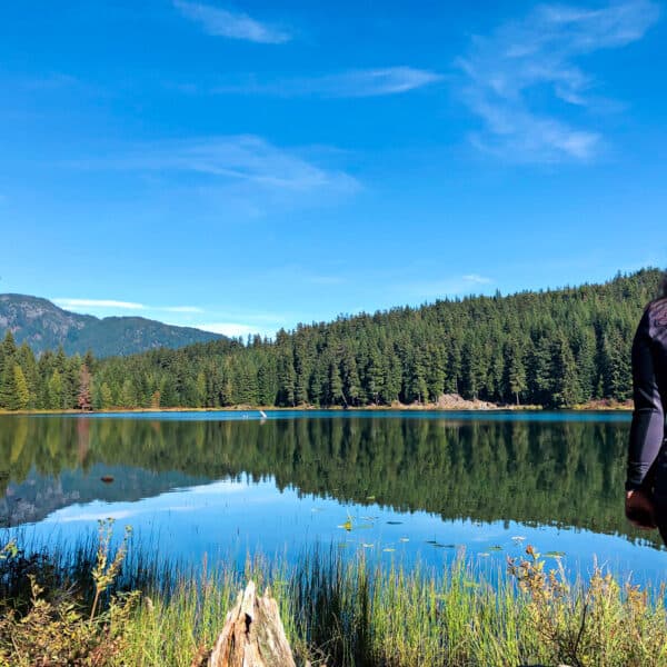 Girl staring out a lake surrounded by trees