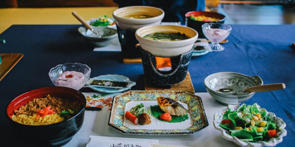 Several small dishes with Japanese food on a table with a blue tablecloth