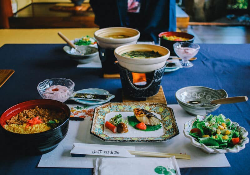 Several small dishes with Japanese food on a table with a blue tablecloth