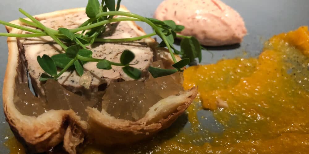 Duck liver spread on a piece of bread with a yellow-orange sauce