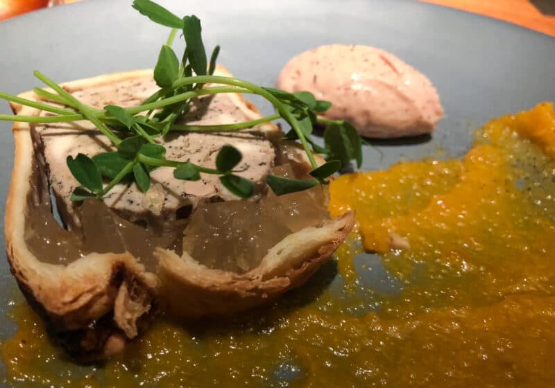 Duck liver spread on a piece of bread with a yellow-orange sauce