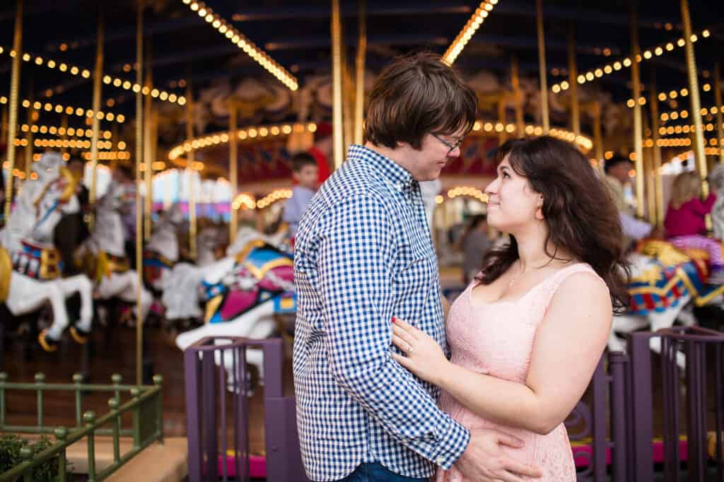 Boy and girl embracing in front of carousel