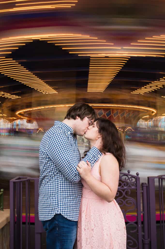 Boy and girl kissing in front of spinning carousel