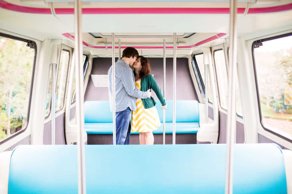 Boy and girl embracing and kissing in a brightly colored monorail car