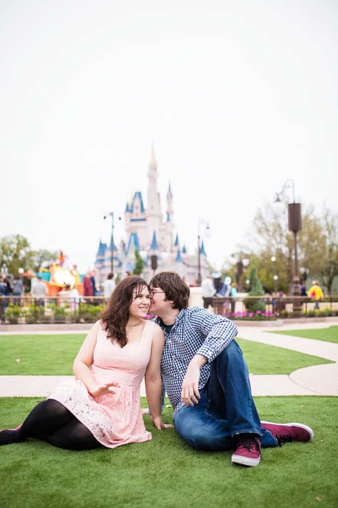 Boy and girl cuddling on the lawn in front of DisneyWorld castle