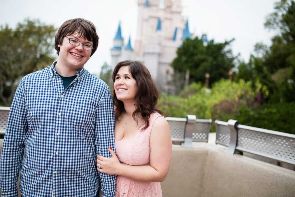 Girl clutching boys arm smiling in front of DisneyWorld castle