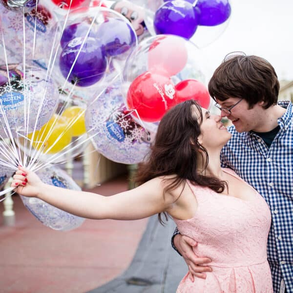 Girl holding balloons kissing boy