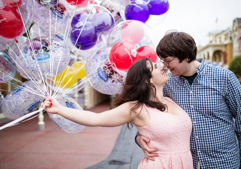 Girl holding balloons kissing boy