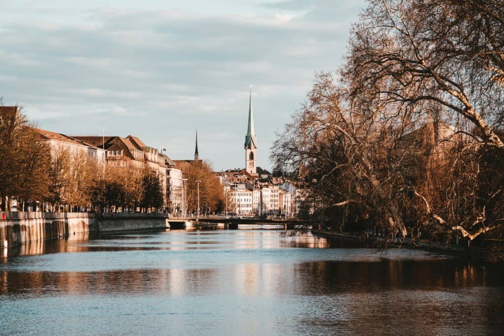 Large spire church in the background with a river leading up to it (Zurich)