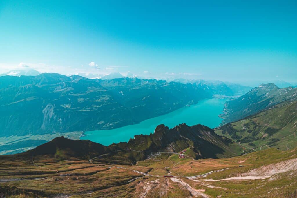 View of the turquoise Lake Brienz from the Brienz Rothorn with the red train running across the hillside