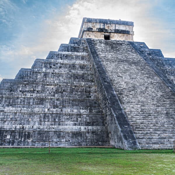Large stone pyramid with stairs ascending up the front and a small window at the top.