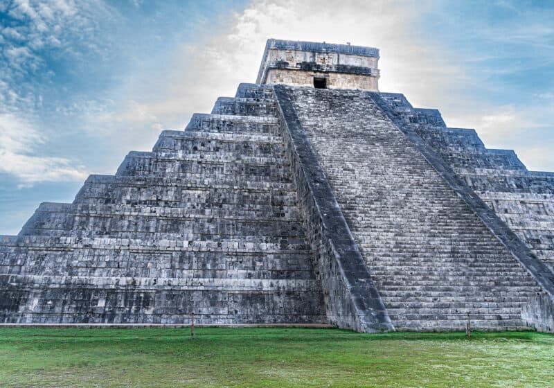 Large stone pyramid with stairs ascending up the front and a small window at the top.